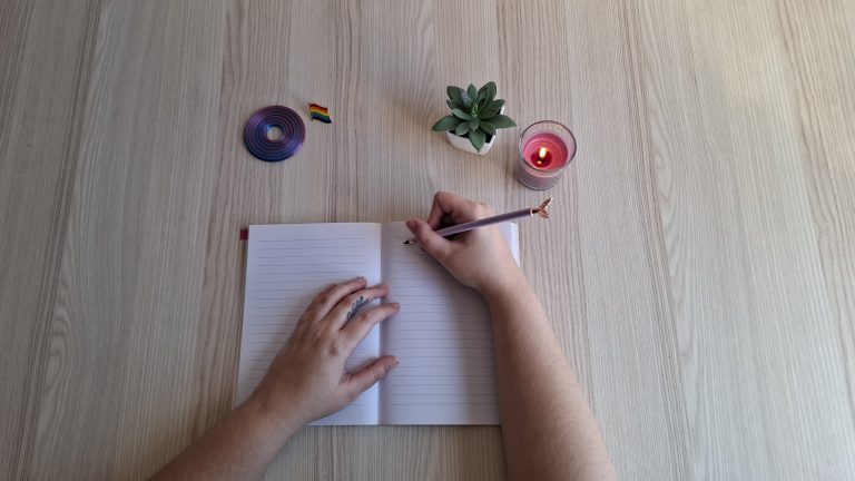 Mano escribiendo en una libreta en un espacio de terapia sexual y de pareja inclusivo hacia personas neurodivergentes y LGTBIQA+