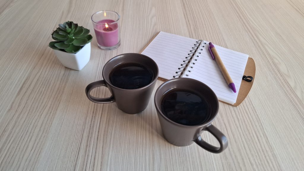 Espacio de acompañamiento en terapia sexual y de pareja con dos tazas de café, libreta y vela